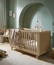 Oska oak cotbed with slatted sides and arch headboard, with star-pattern blanket