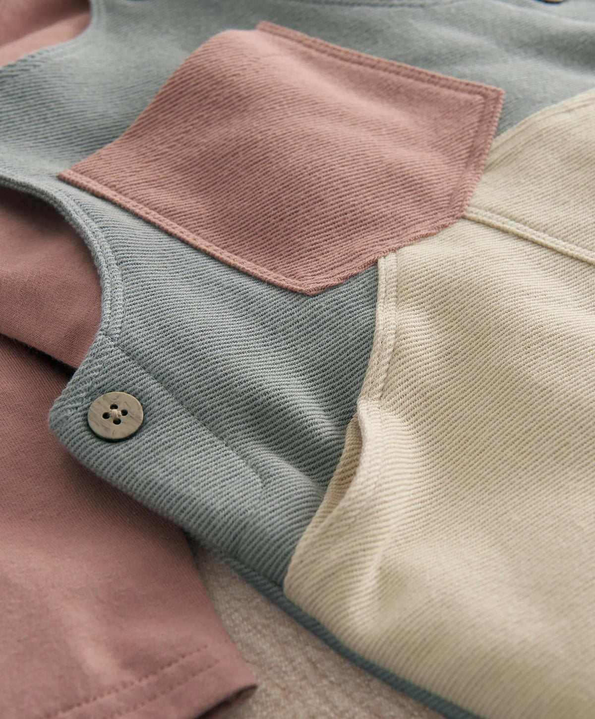 Color-block dungarees close-up: round buttons and stitched square chest pocket