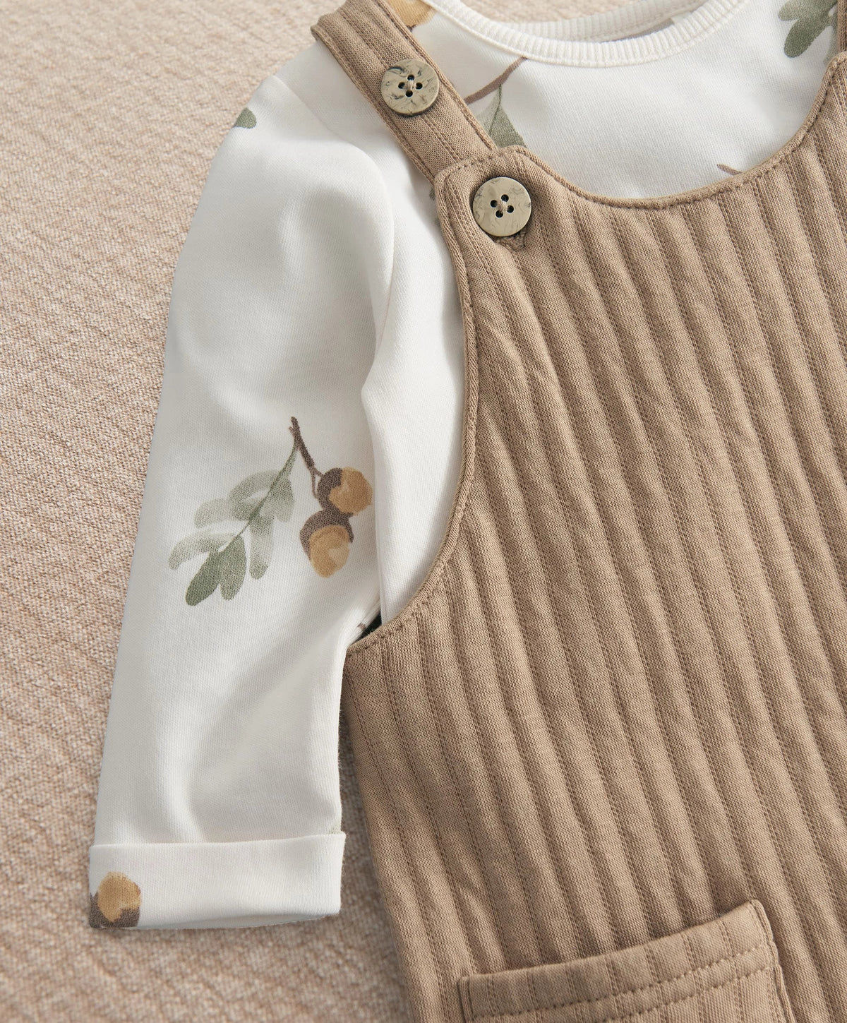 Baby dungaree and bodysuit set close-up: tan overalls bib with button straps