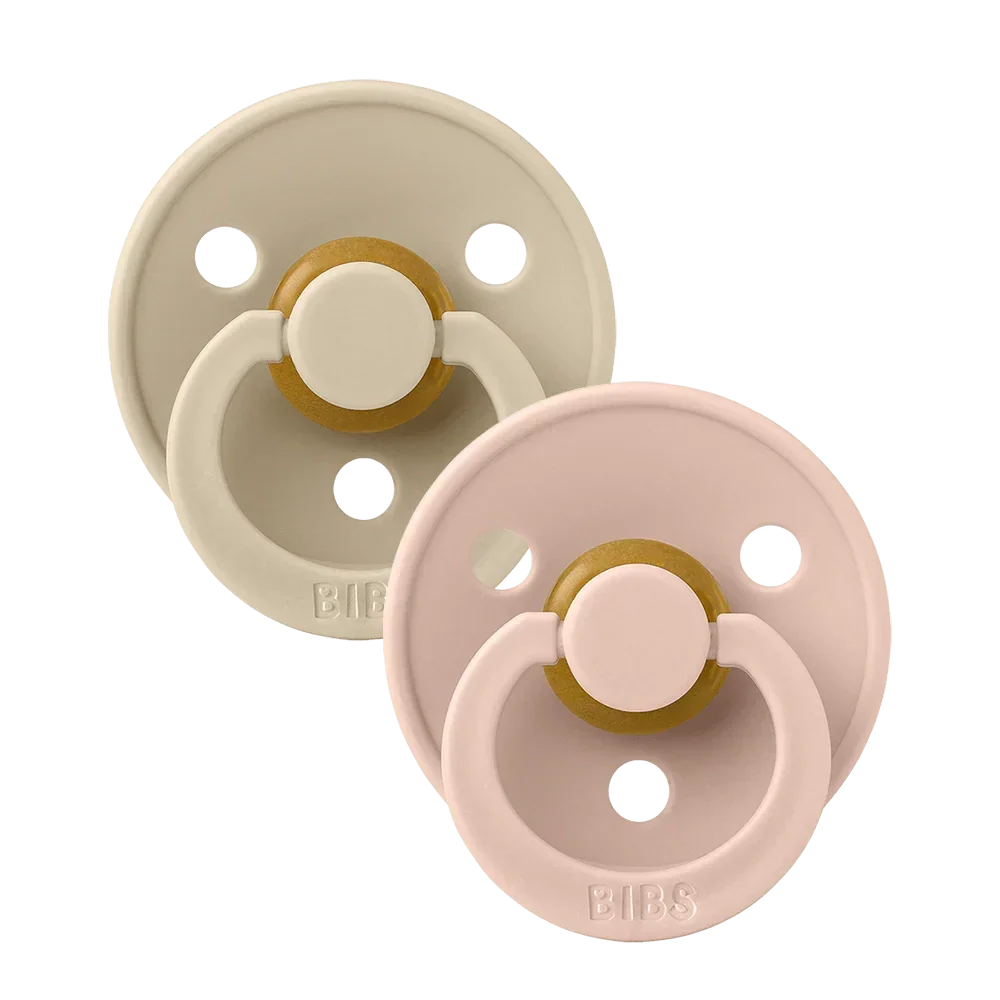 Two round latex baby pacifiers, blush pink and vanilla beige with gold accents