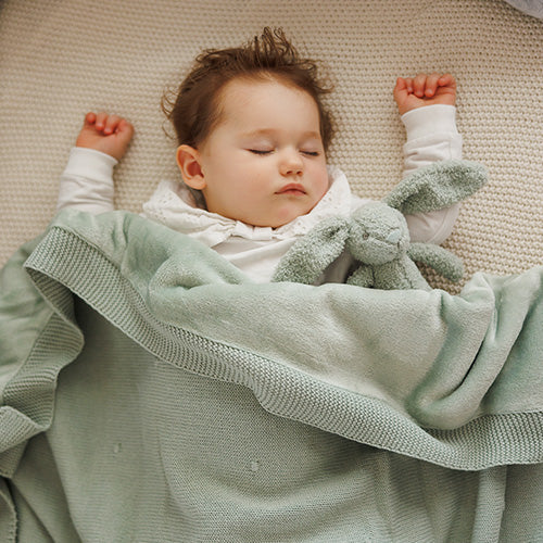 Light green flannel-lined cotton blanket wrapped around sleeping baby