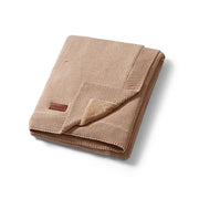 Cotton blanket with flannel lining, folded tan with stitched edge and small label
