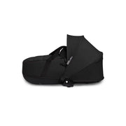 Black newborn carrycot with foldable hood and carry handle, shown on its side.