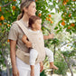 Beige hip seat baby carrier worn in side position with adjustable shoulder straps