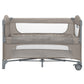 Beige two-level baby cot with mesh side openings and padded mattress platforms