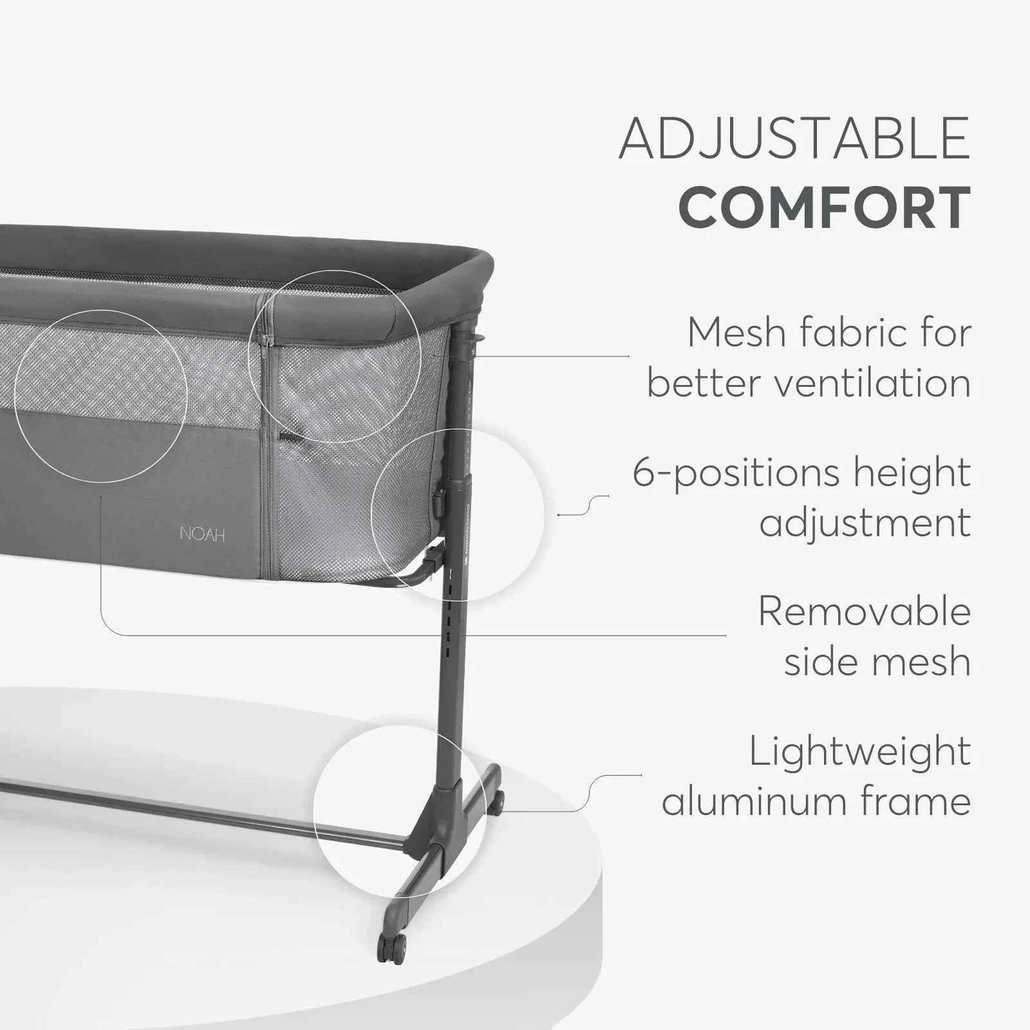 Dark grey bedside crib side view with removable mesh panel and adjustable height