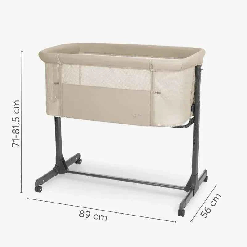Light grey bedside crib with padded top, mesh sides, and rolling aluminum stand