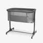 Dark grey bedside crib with padded top, mesh sides, and wheeled aluminum frame