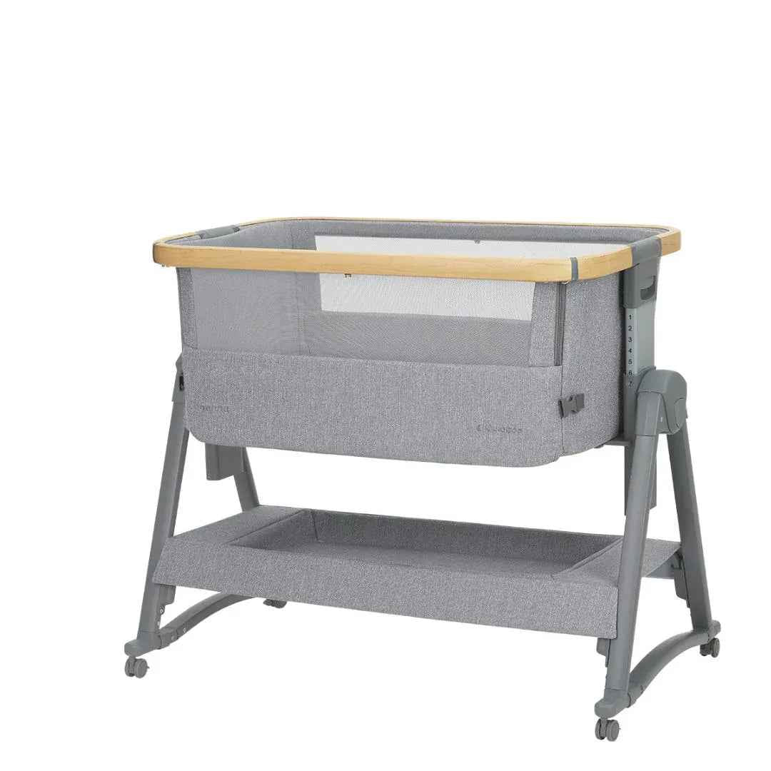 Grey bedside crib with open top mesh, wooden edge bar, and two-tier frame on casters