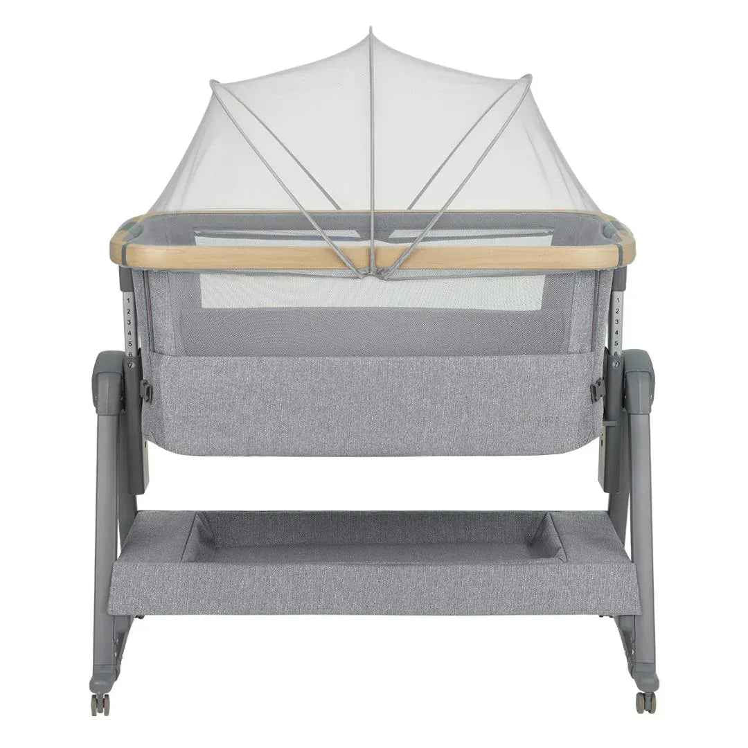Grey bedside crib with arched fabric canopy and mesh panel, two-level base, caster feet