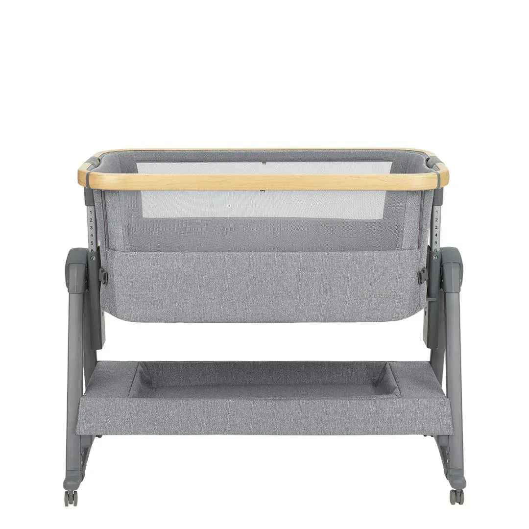 Grey bedside crib with mesh side panels, wooden top bar, and two-tier platform base