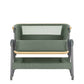Army green bedside crib with raised front panel, white mesh window, and wooden base rail