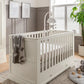 Off-white cot bed with vertical slat rails and side panel, corner knob