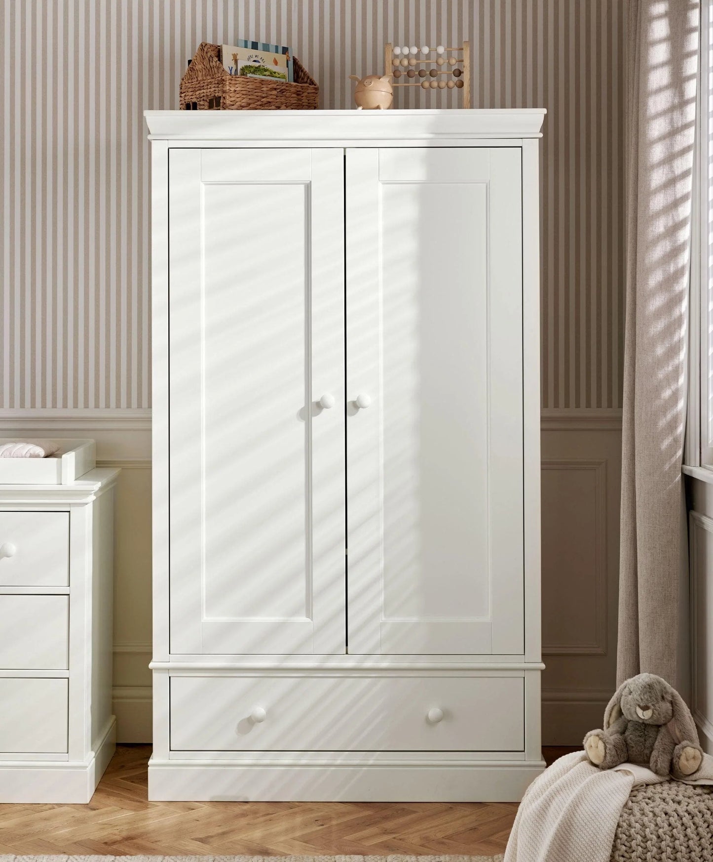 Off-white nursery wardrobe with two door panels and a bottom storage drawer