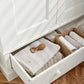 Off-white wardrobe storage drawer open with folded fabric and small woven baskets