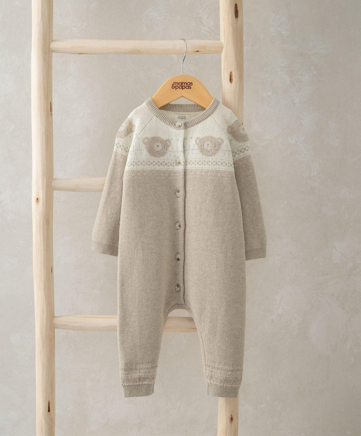 Light beige knitted romper with long sleeves, button front, and teddy bear face motif