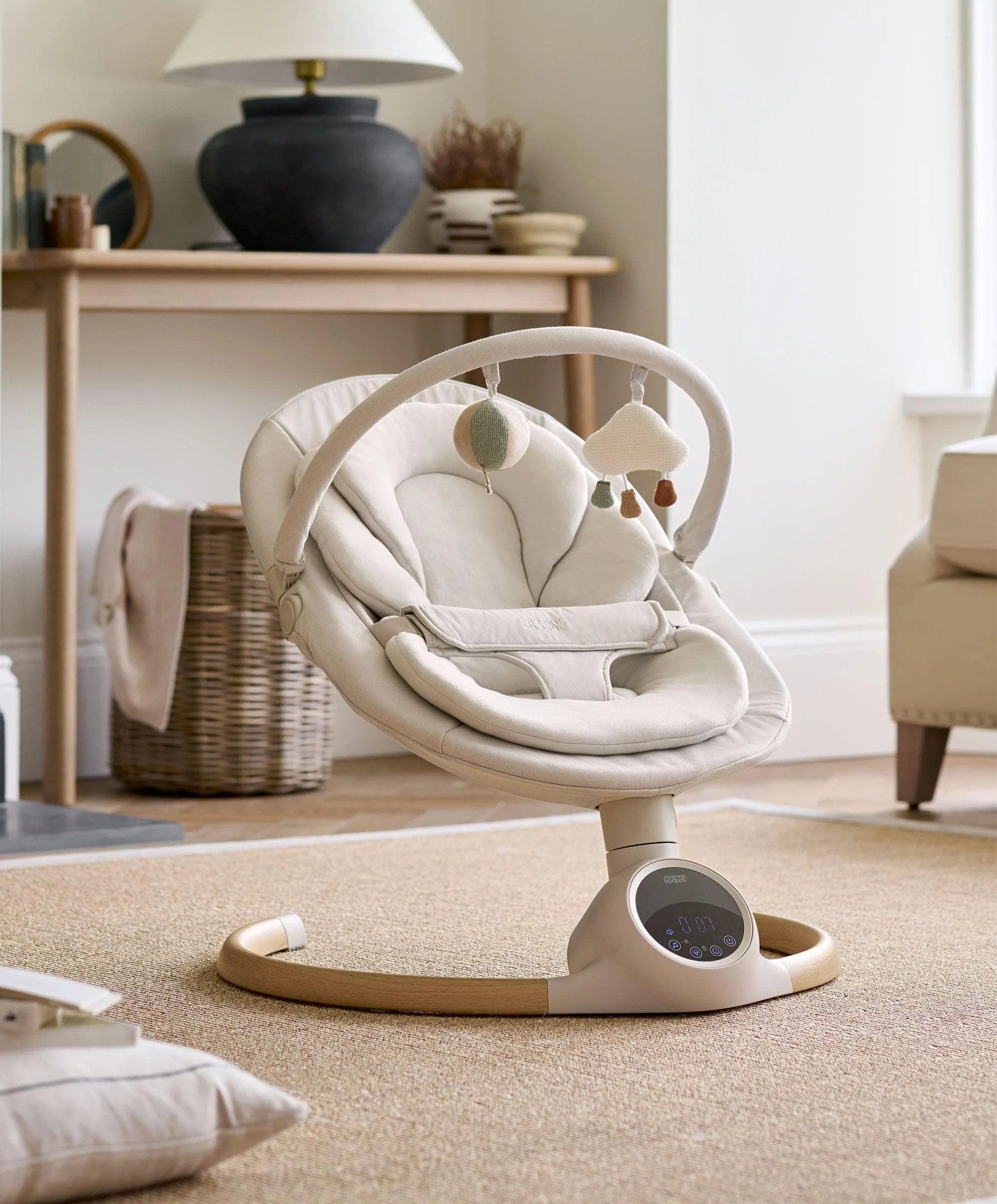 Cream baby swing side view with cushioned seat and dangling toy arch.