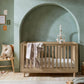 Oak cotbed with slatted rail and draped star-pattern blanket, arch back