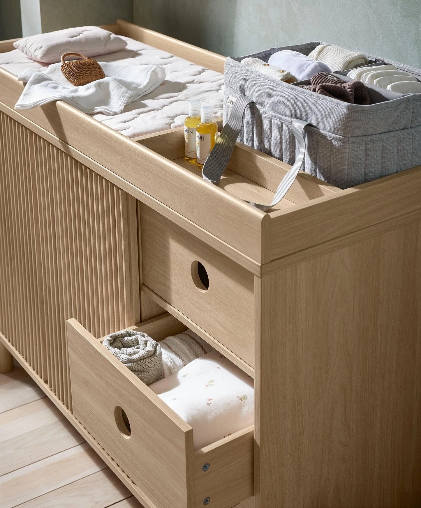 Oak wide dresser changer with open drawer and organizer bins on the changing top