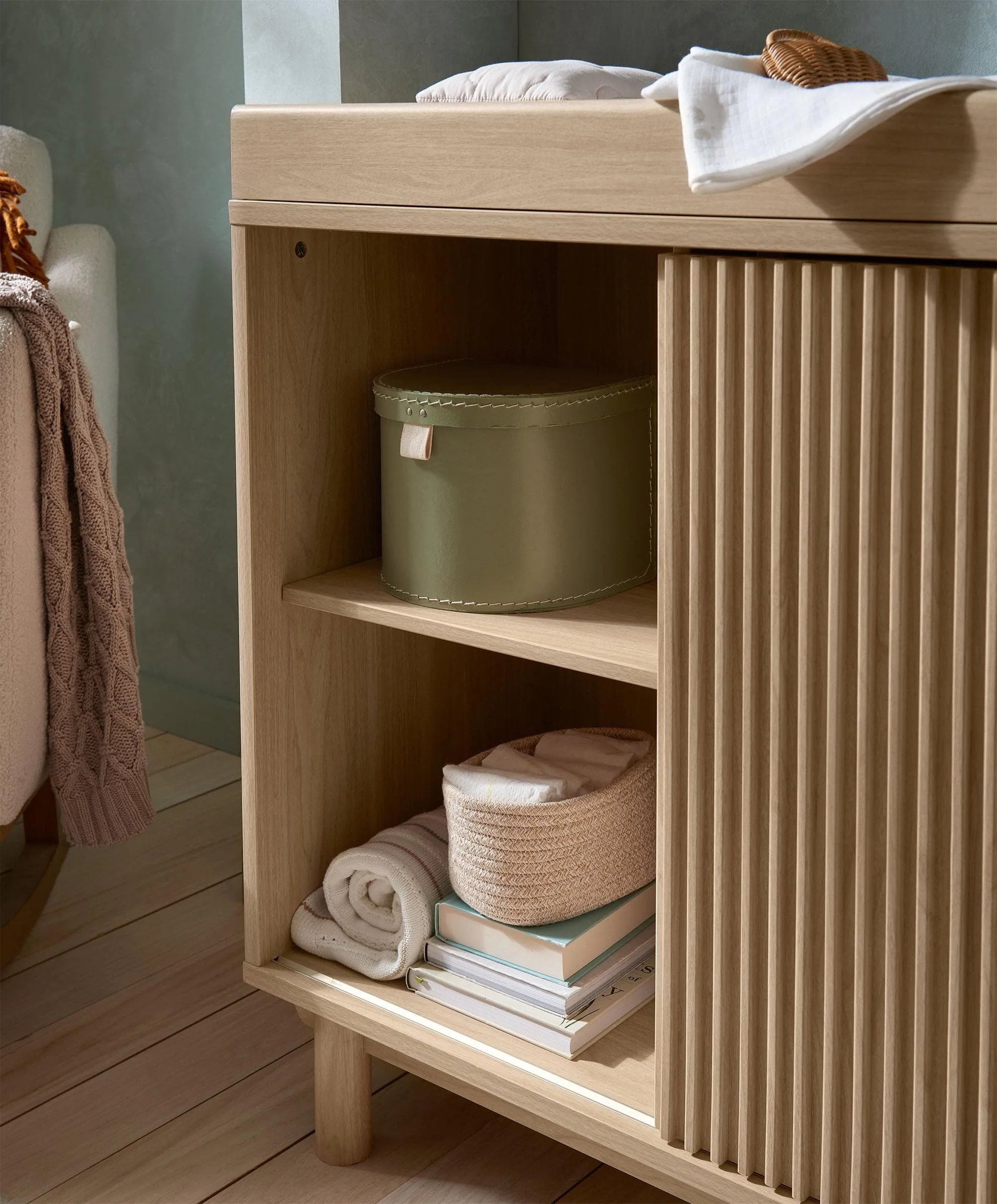 Oak wide dresser changer with open shelf showing baskets and stacked folded linens