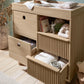 Light oak changing dresser with open cubbies, ribbed drawer fronts, and side cabinet
