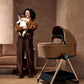 Carrycot stand with light beige carrycot, wooden legs, and dark base