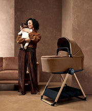 Carrycot stand with light beige carrycot, wooden legs, and dark base