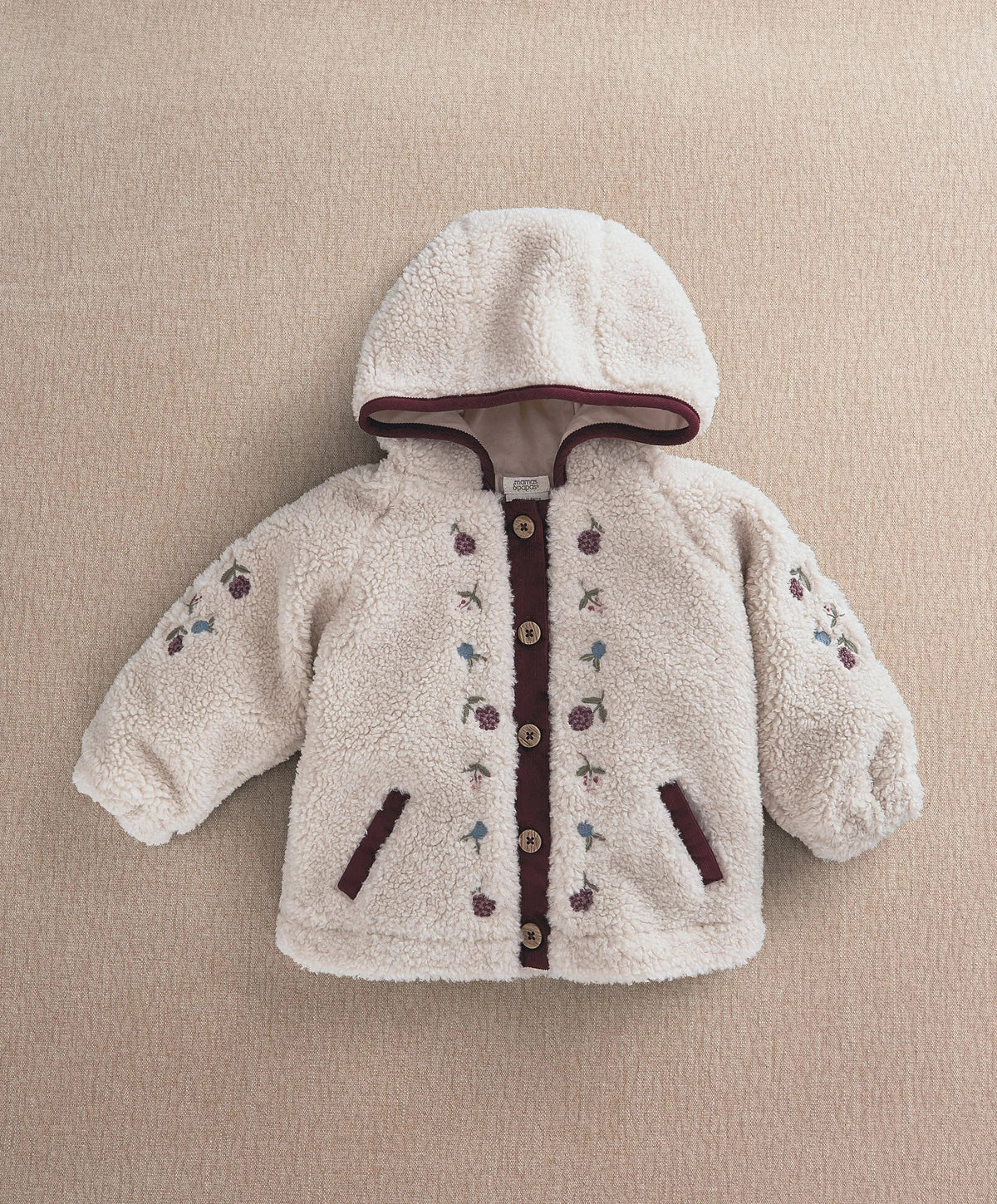 Cream hooded borg jacket with burgundy zipper trim and embroidered sleeve motifs