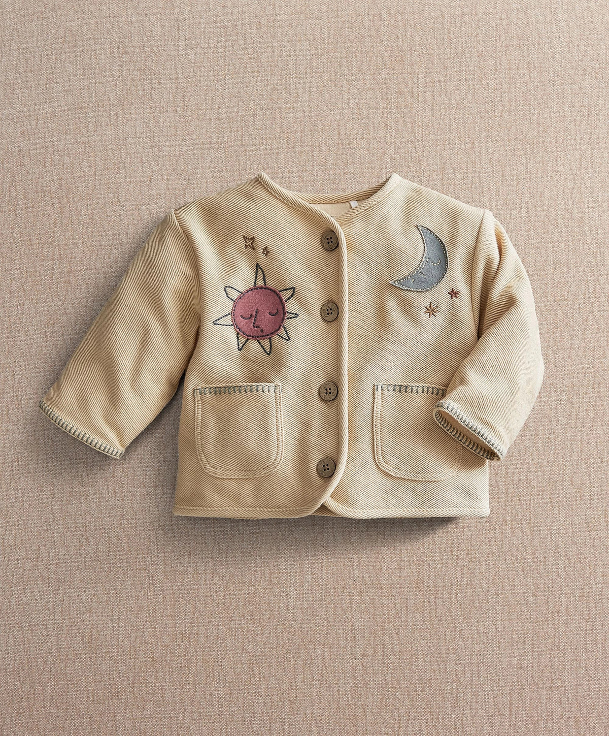 Cream kids jacket with front buttons, sun and moon embroidery, and two chest pockets