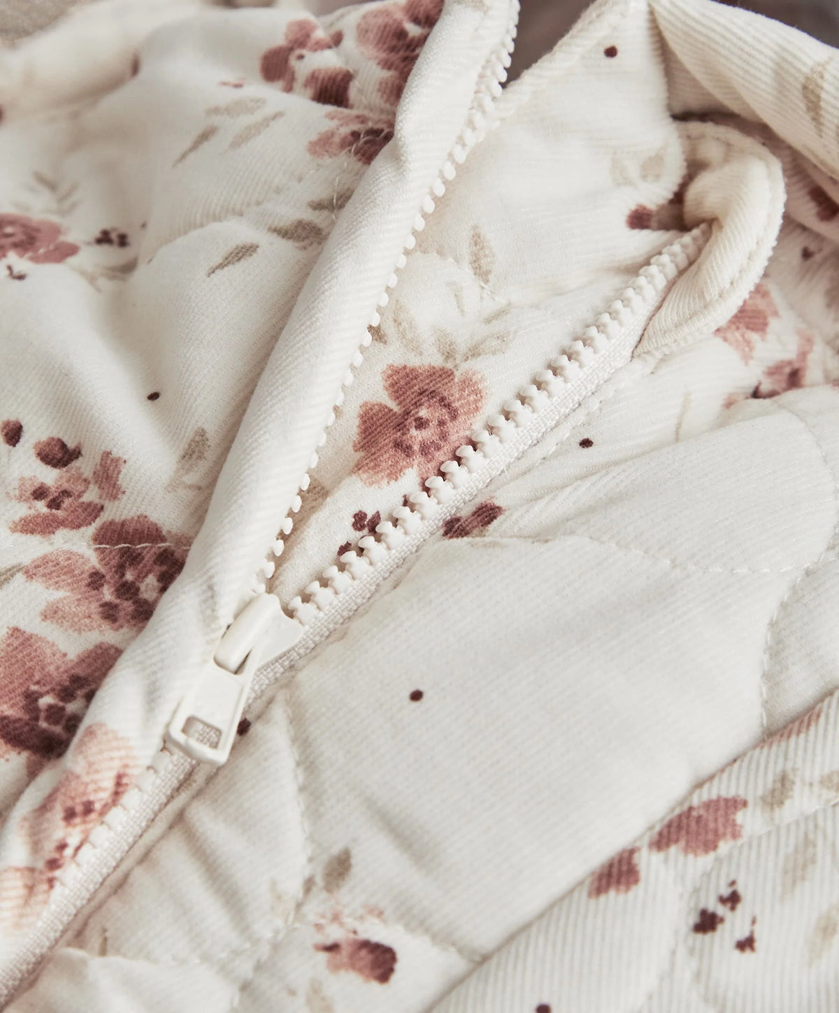 Ditsy print pramsuit close-up with full-length zip and floral knit lining