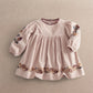 Light pink embroidered corduroy dress with long puff sleeves and floral hem border