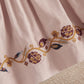 Light pink corduroy dress with floral embroidered hem on pleated skirt