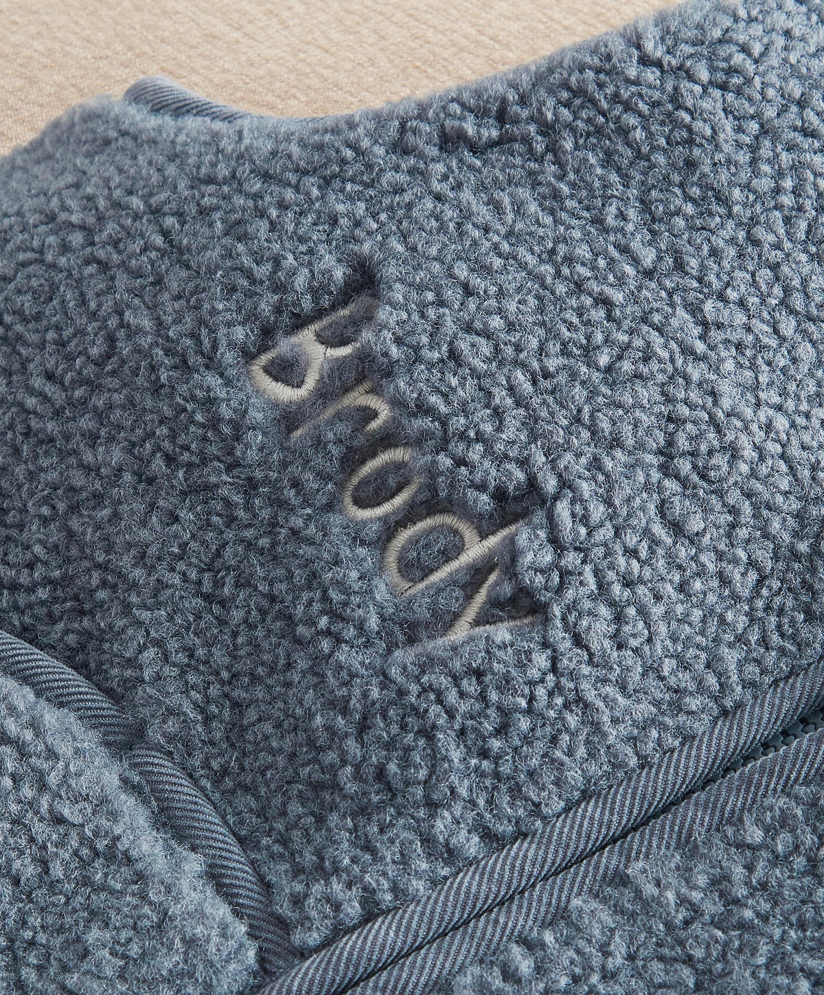 Blue sherpa fleece gilet close-up of 'BORN' applique and rib trim
