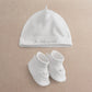 White baby beanie hat and booties set with cursive text accents