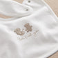 White baby bib with brown animal celebration embroidery and snap closure