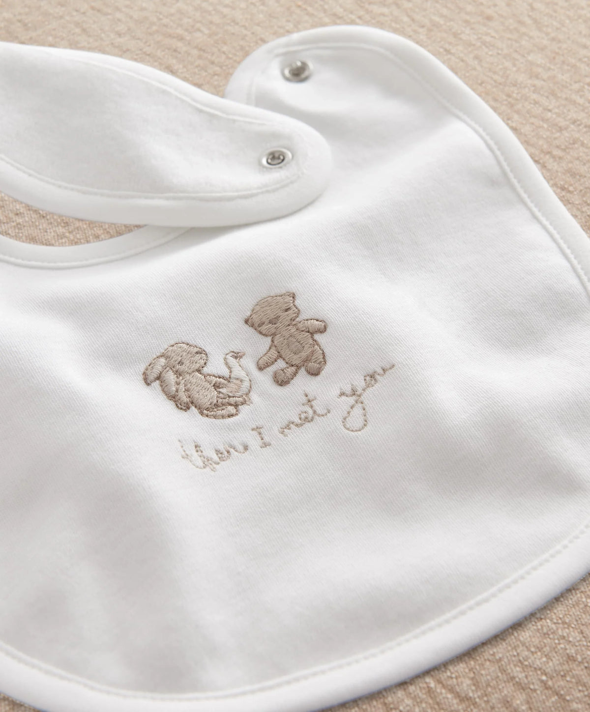 White baby bib with brown animal celebration embroidery and snap closure