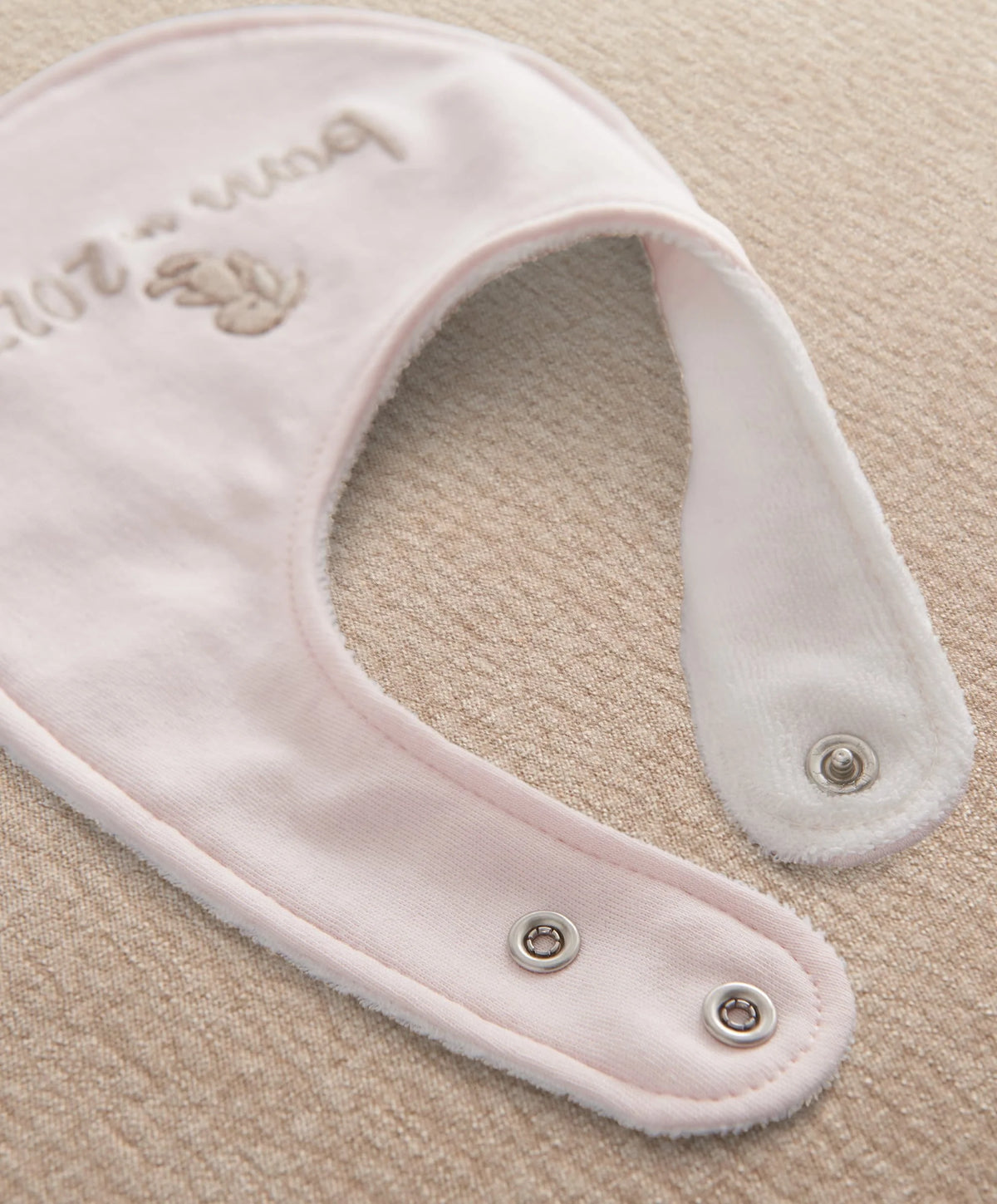 Pink baby bib with snap buttons at bottom and embroidered 'born in 2027'