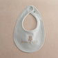 Light blue baby bib with round neck opening and embroidered teddy "Born in 2027"