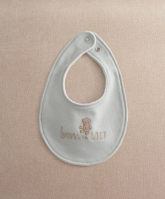 Light blue baby bib with round neck opening and embroidered teddy "Born in 2027"