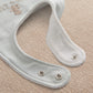 Light blue baby bib with snap buttons and curved neckline trim
