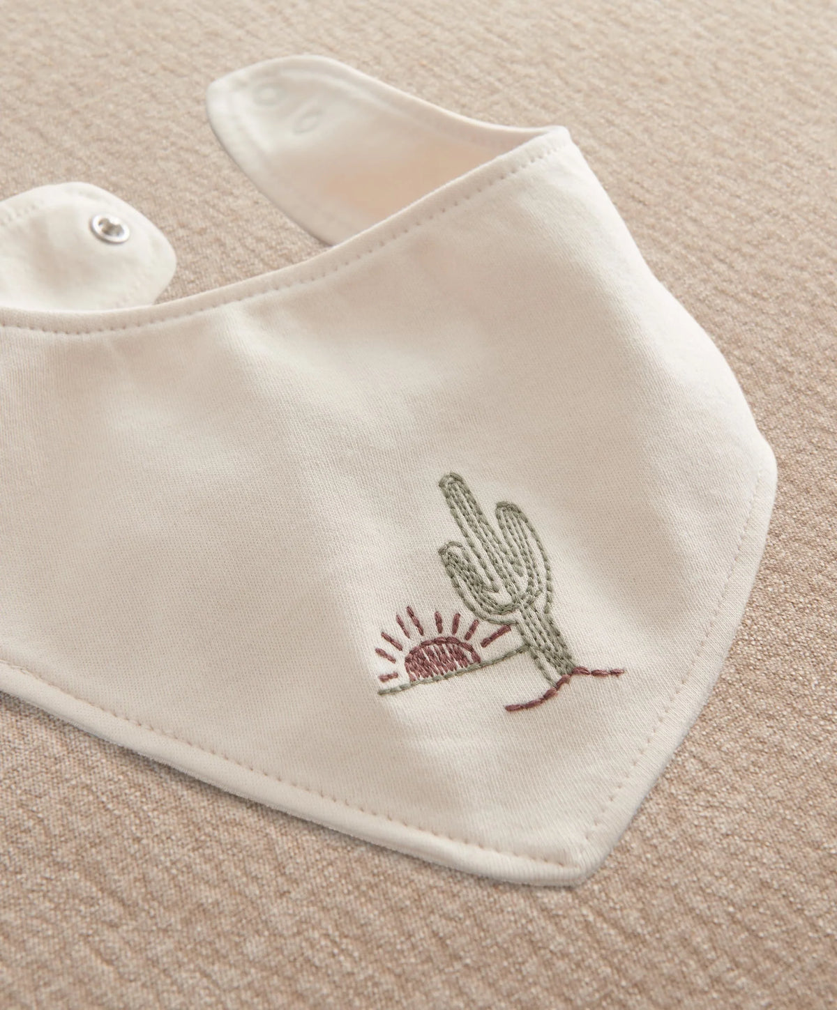 White bandana bib with green cactus embroidery and snap closure