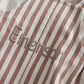 Close-up of brown-and-cream vertical stripe fabric with stitched script detail