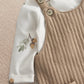 Baby dungaree and bodysuit set close-up: tan overalls bib with button straps