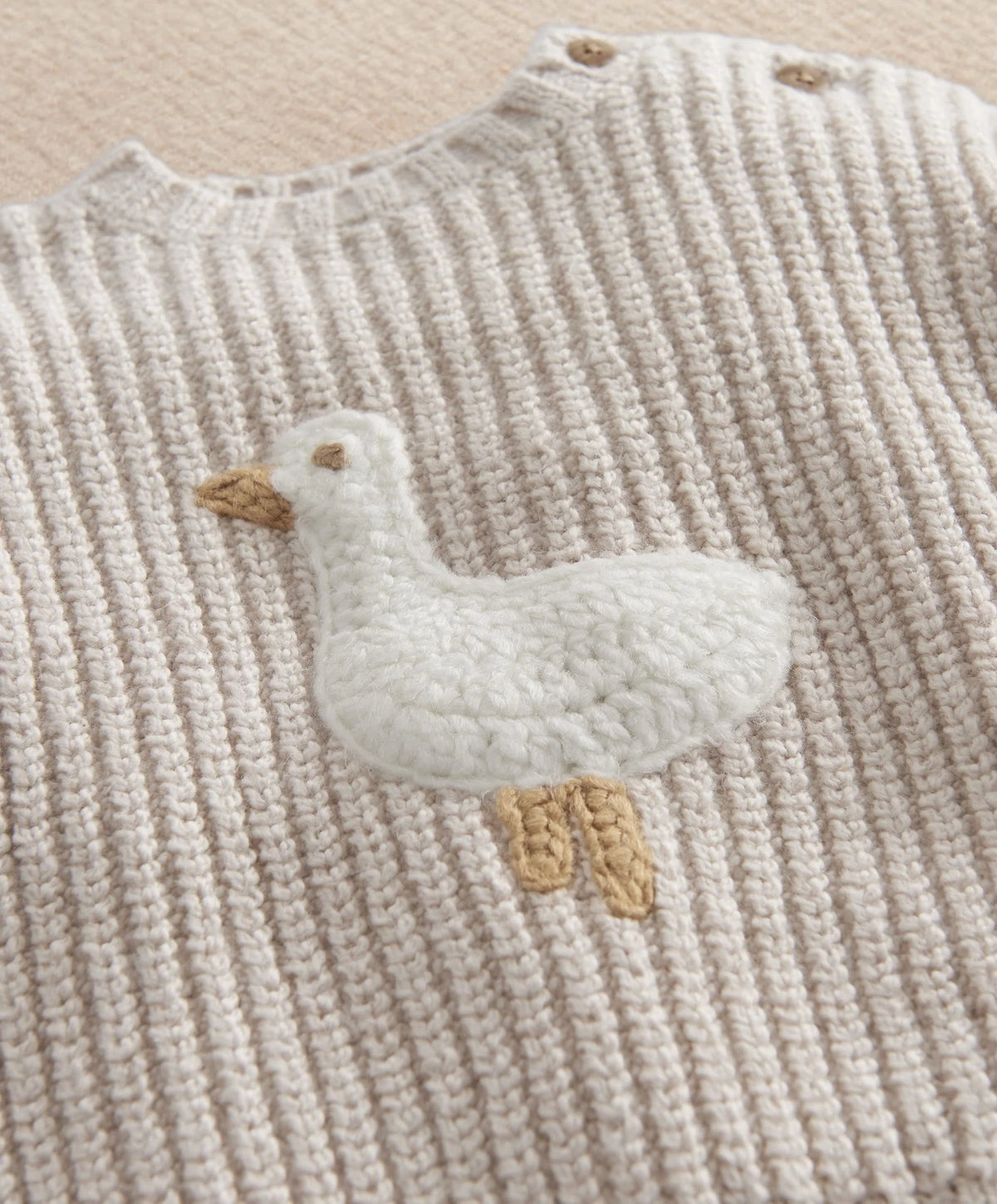 Cream knit sweater with duck applique on chest, ribbed texture, long sleeves