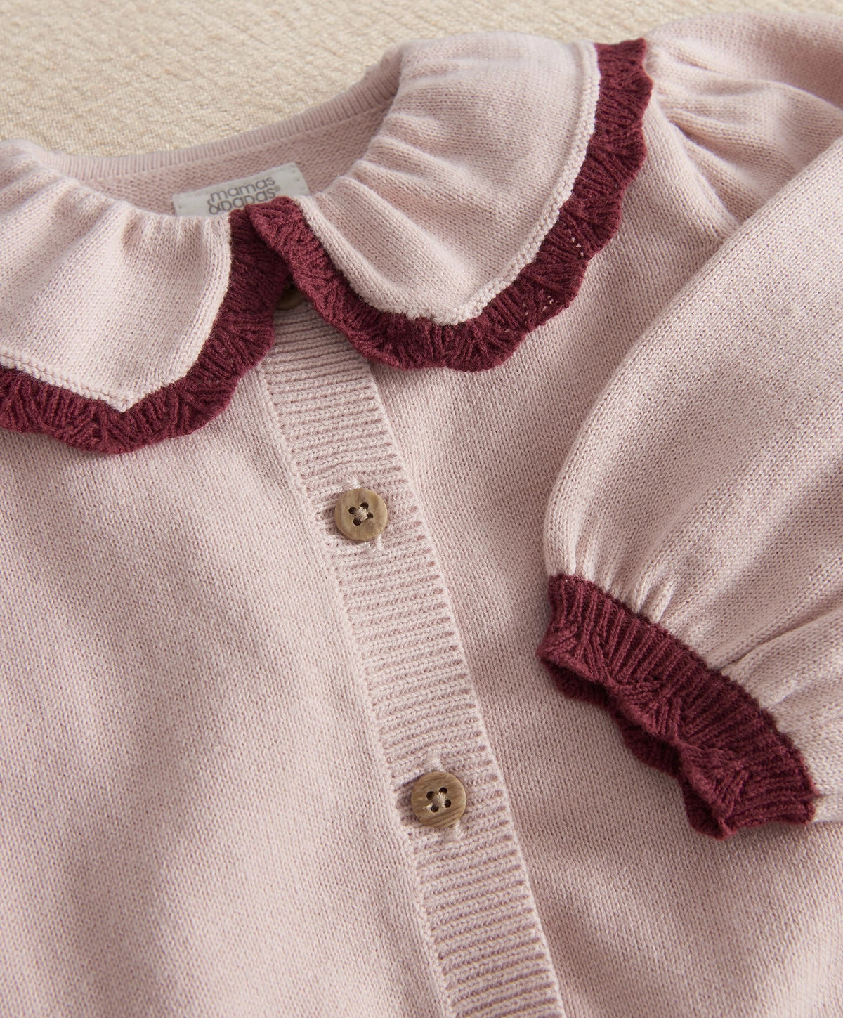 Light pink knit cardigan top with button placket, maroon collar and cuffs