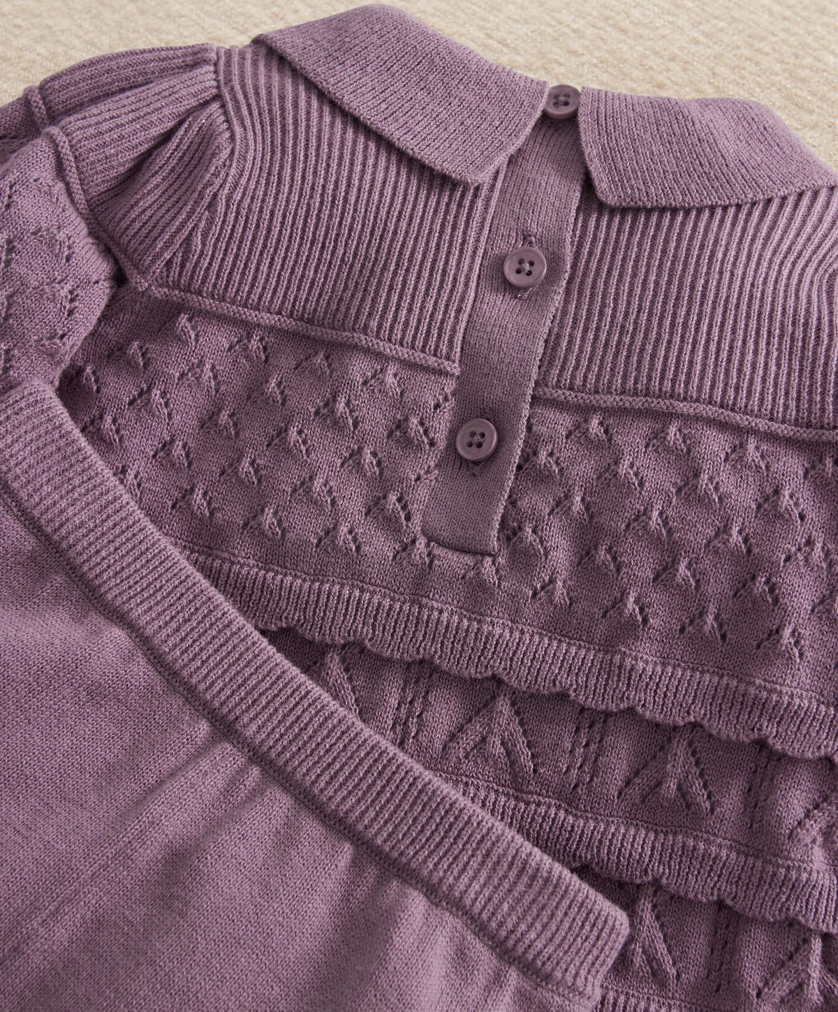 Plum knit cardigan-style top with ribbed collar, buttons, and textured yoke