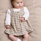 Toddler gingham dress over long-sleeve white bodysuit, tan and cream check with green detail