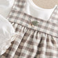 Gingham plaid dress bodice with gathered ruffle yoke over white long-sleeve bodysuit