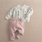 Cream embroidered knit cardigan with button front and mauve knit leggings, flat lay.