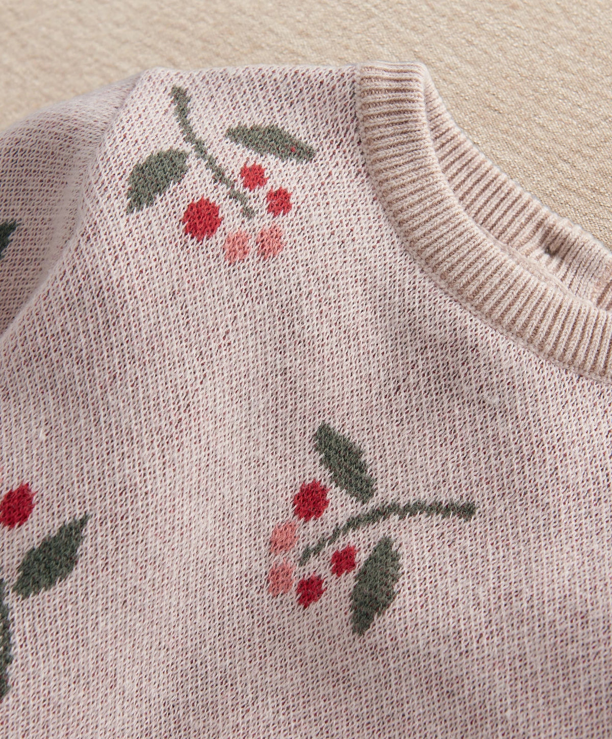 Pink knitted top with berry and leaf print, ribbed crew neckline
